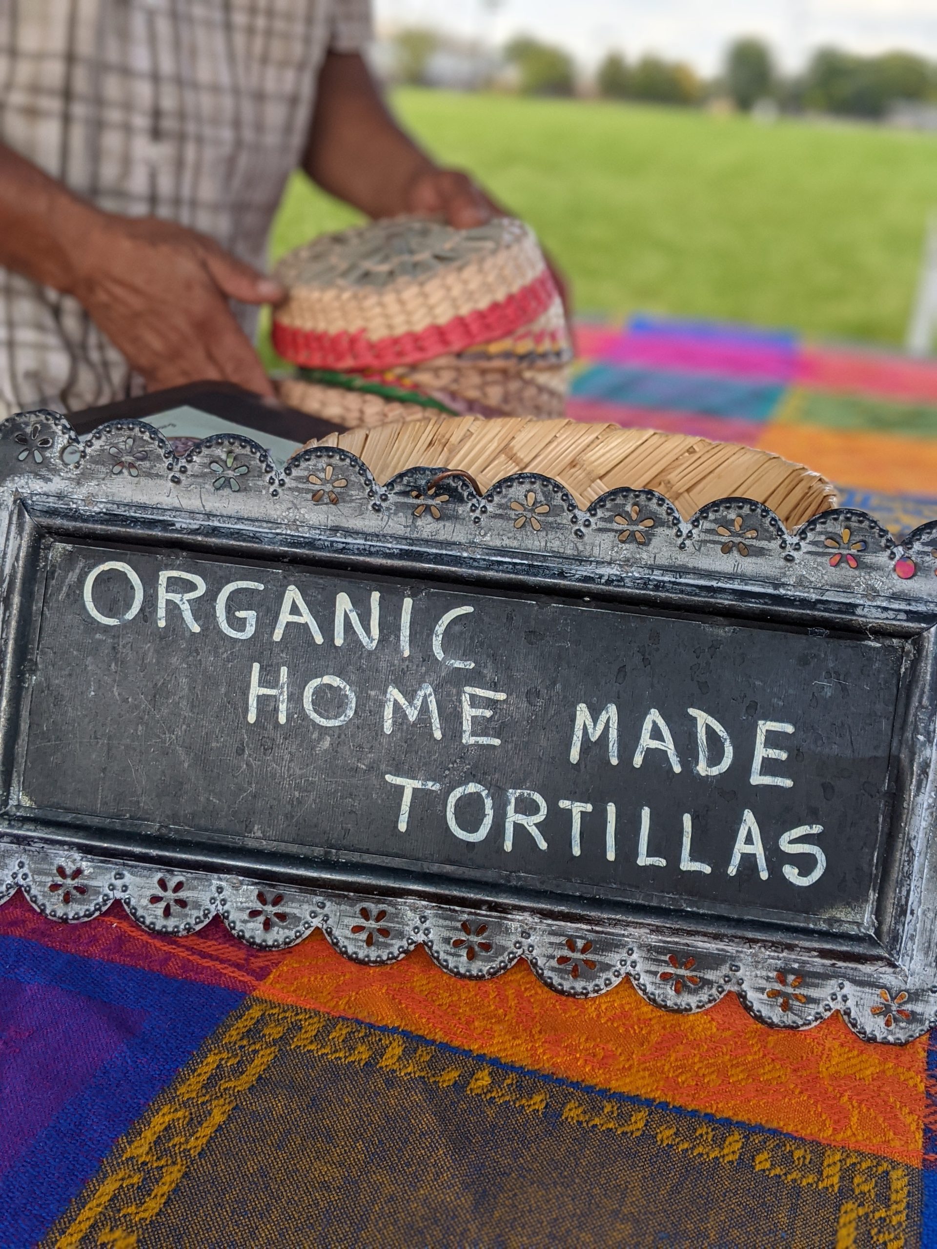 Chalkboard sign at farmers market that reads "Organic Home Made Tortillas"